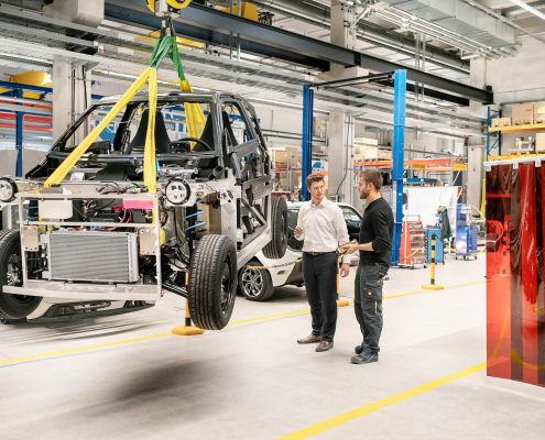 In einer Industriehalle hängt ein Auto am Kran.